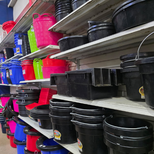 Store shelves display a variety of colorful plastic tubs and buckets, with stacks of blue, red, pink, and black colors, creating a vibrant, organized setting.