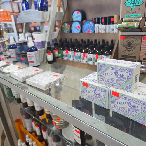 Shelves filled with a variety of skincare products, including tallow soap and essential oils. The display conveys an artisanal, natural vibe.